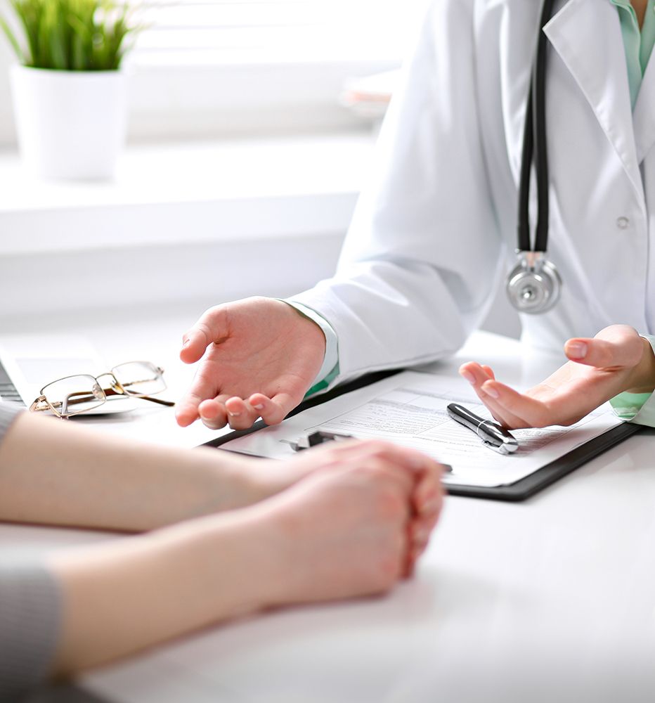 Ein Arzt im weißen Kittel gestikuliert im Gespräch mit einem Patienten